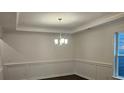 Dining room featuring paneled walls, dark floors, a hanging chandelier, and natural light at 8231 Annsborough Nw Dr, Concord, NC 28027