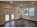 Living room with dark floors, french doors to the backyard, and natural light from three windows at 8231 Annsborough Nw Dr, Concord, NC 28027