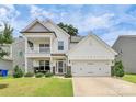 Inviting two-story home with a charming front porch and a two-car garage, complemented by a green lawn at 139 Suggs Mill Dr, Mooresville, NC 28115