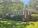 A charming brick house showcases its side profile, surrounded by greenery, and topped with a classic roof and white trim at 2120 Marwood Ln, Albemarle, NC 28001