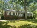 Inviting single-story brick home with white-trimmed windows and a lush, green front yard under the shade of mature trees at 2120 Marwood Ln, Albemarle, NC 28001
