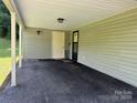 View of a carport featuring a door to the side, lighting, and asphalt driveway at 227 James Rd, Taylorsville, NC 28681