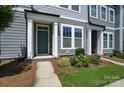 Inviting townhome exterior featuring gray siding, white trim, a well-maintained lawn, and a teal front door at 334 Ladybird Ln, Pineville, NC 28134