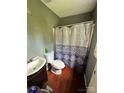 Compact bathroom with laminate floor, toilet, vanity, and shower with blue shower curtain at 3396 Farm Lake Sw Dr, Concord, NC 28027