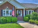 Beautiful brick home entrance with manicured bushes, arched windows, and an American flag at 5921 Meadowmere Dr, Monroe, NC 28110