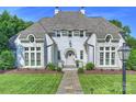 Beautiful white painted brick home with arched door, stone details, and manicured front lawn at 6314 Saint Stephen Ln, Charlotte, NC 28210