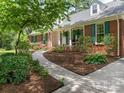 Well-maintained brick home with walkway, mature landscaping, and covered front porch at 7118 Powder Mill Pl, Charlotte, NC 28277