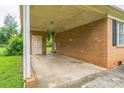 Spacious covered carport adjacent to the brick house with door and brick wall at 1019 Carmel Dr, Gastonia, NC 28056