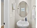 A quaint powder room with a pedestal sink, oval mirror, and neutral decor provides a clean and simple design at 11195 Argosy Dr # 1098, Lancaster, SC 29720