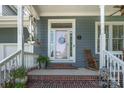 Inviting front porch with rocking chair, plants and view of the two-car garage of this charming two-story home at 138 Blandina Ct, Fort Mill, SC 29708