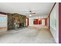 Spacious living room featuring stone fireplace, carpeted floors and ample natural light from plantation shutters at 13909 Idlewild Rd, Matthews, NC 28105