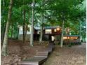 Inviting home exterior with mature trees, wooden deck, and exterior stairs at 143 Uwharrie Ct # 10801081, Mount Gilead, NC 27306