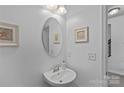 Elegant half bath with pedestal sink, oval mirror, and coastal-themed decor at 1527 Scarbrough Sw Cir, Concord, NC 28025