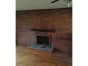 Cozy living room highlighting a brick fireplace and hearth with hardwood flooring at 1700 Old Spencer Mountain Rd, Dallas, NC 28034