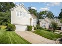 View of a well-manicured lawn and driveway leading up to a cream-colored two-story house with an attached garage at 220 Holmes Ct, Concord, NC 28027