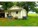 Backyard view of cozy home featuring green yard, sheds, and mature landscaping at 238 Deaton St, Statesville, NC 28677