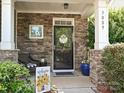 Inviting front porch with stone accents, adorned with a welcome sign and potted plants at 3009 Canopy Dr, Indian Trail, NC 28079
