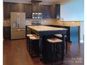A modern kitchen featuring dark cabinets, stainless steel appliances, and a large granite island with seating at 3717 English Garden Dr, Gastonia, NC 28056