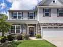Inviting two-story home featuring a stone facade, a two-car garage, and a cozy front porch at 4014 Stockbrook Dr, Charlotte, NC 28215