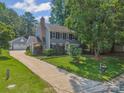 View of home's exterior, detached garage, driveway, and manicured lawn at 4911 Rivergreen Ln, Charlotte, NC 28227