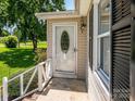 Close-up of the home's front door, showcasing the decorative glass insert and white trim, with a partial view of the yard at 618 Springfield Nw Dr, Concord, NC 28027