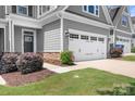 Close up view of the two-car garage with white doors and a grassy lawn at 6365 Ashton Park Dr, Denver, NC 28037