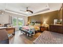 Comfortable main bedroom with a tray ceiling, fan, and ample natural light from the large windows at 6412 Bluegill Rd, Charlotte, NC 28216