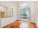 Bright dining room featuring hardwood floors, wainscoting, and a large window overlooking the front yard at 6414 Goldenblush Cir, Charlotte, NC 28269