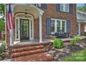 Welcoming front porch with brick steps, an arched entry, bench and neat landscaping at traditional brick home at 726 E Kingston Ave, Charlotte, NC 28203