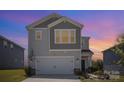 Two-story home with gray siding, a front-facing two-car garage, and meticulously landscaped yard at dusk at 1010 Harry Ct, Albemarle, NC 28001