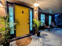 Close-up of front entrance with a yellow door, dark trim, porch lights, and greenery at 11419 Leadenhall Ln, Charlotte, NC 28262