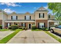 Inviting townhome showcasing a well-maintained lawn, brick accents, and a convenient carport for covered parking at 222 Ross Moore Ave, Charlotte, NC 28205