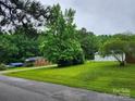 Landscaped yard with mature trees surrounding a charming single-story brick home at 2448 Cambridge Dr, Lancaster, SC 29720