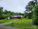 Quaint single-story brick home with covered parking, lush lawn, and mature trees at 2448 Cambridge Dr, Lancaster, SC 29720
