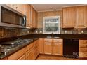 Kitchen featuring warm maple cabinets, a stainless steel microwave, and a complementary backsplash at 6117 Yellowood Rd, Charlotte, NC 28210