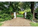 Inviting backyard entrance through white brick pillars and wooden gate surrounded by lush greenery at 802 E Franklin St, Monroe, NC 28112