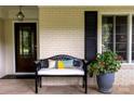 Charming front porch features a cozy bench, decorative pillow, and lovely potted flowers at 802 E Franklin St, Monroe, NC 28112