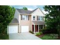 Two-story home with a two-car garage, cozy front porch, manicured bushes, and a well-kept lawn at 1210 Tabitha Ct, Monroe, NC 28110