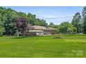 The lush front yard features a fire pit and a charming brick home at 128 Howie St, Mount Holly, NC 28120