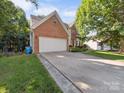 Exterior showcases a long driveway leading to the two-car garage in a brick facade home at 130 Nims Spring Dr, Fort Mill, SC 29715