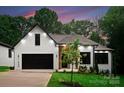 Beautifully landscaped front exterior showcasing a white brick facade, dark trim, and a modern black garage at 1622 Burtonwood Cir, Charlotte, NC 28212