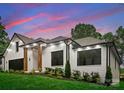 A beautifully landscaped front exterior featuring a white brick facade, black trim, and well-manicured greenery at 1622 Burtonwood Cir, Charlotte, NC 28212