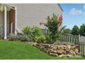 Landscaped yard featuring a rock wall, a wooden fence, blooming bushes, and verdant greenery at 1986 Trace Creek Dr, Waxhaw, NC 28173