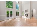 Bright living room with soaring windows, light wood floors, fireplace, and access to a deck at 3011 Mckee Rd, Charlotte, NC 28270