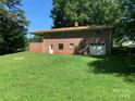 View of the backyard featuring a brick house with a garage, grassy area and patio at 3484 S Hwy 127 Hwy, Hickory, NC 28602