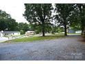 View of the front lawn with trees and a gravel driveway at 416 E Union St, Marshville, NC 28103