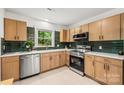 Modern kitchen with stainless steel appliances, light wood cabinets and green backsplash at 5320 Kildare Dr, Charlotte, NC 28215