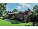 The backyard of a brick house has green grass and trees, with a small patio area at 615 Bell Farm Rd, Statesville, NC 28625