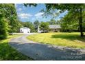 Wide paved driveway leading to a charming home with a garage and a large storage building at 6811 Kluttz Rd, Concord, NC 28025