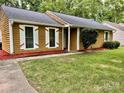 Charming home with yellow siding, white shutters, a walkway, and vibrant red landscaping at 6832 Delta Lake Dr, Charlotte, NC 28215